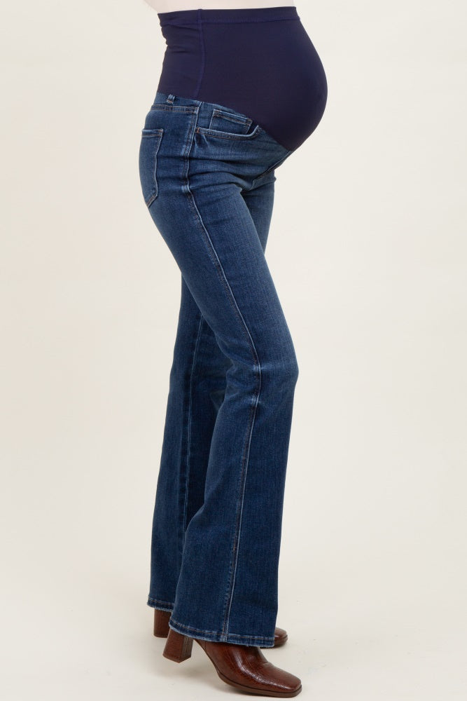woman wearing dark blue maternity flared jeans with a supportive belly panel, showing her baby bump