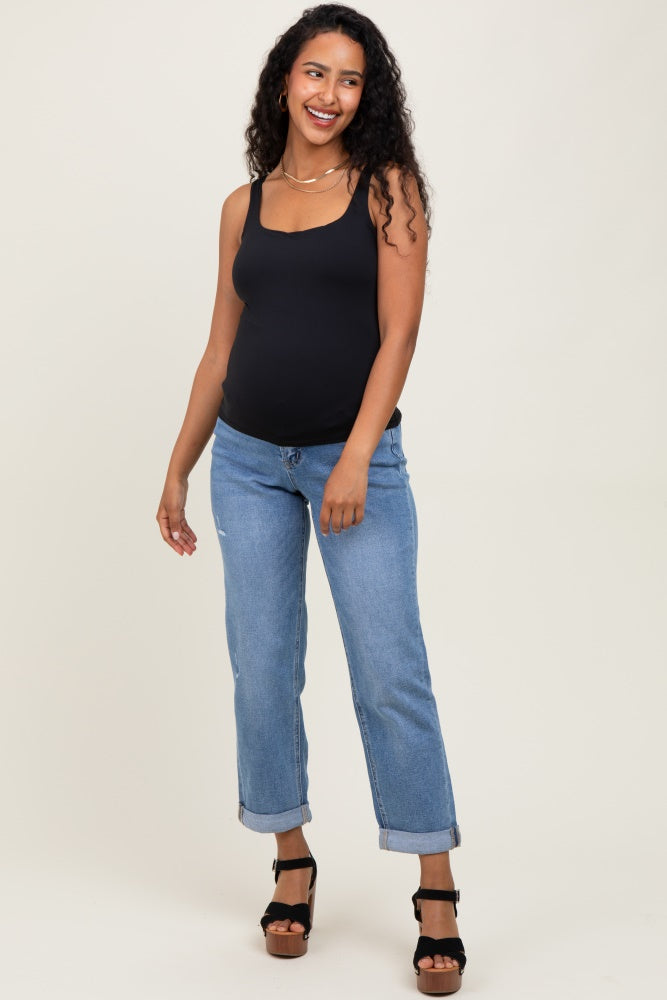 woman wearing a black maternity tank top and blue boyfriend jeans, showing her baby bump