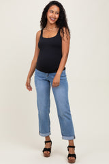 woman wearing a black maternity tank top and blue boyfriend jeans, showing her baby bump