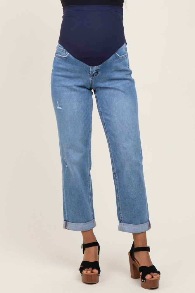 woman wearing light blue maternity jeans with a mid-rise waistband and rolled cuffs, paired with black platform sandals