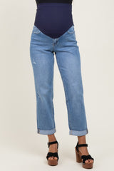 woman wearing light blue maternity jeans with a mid-rise waistband and rolled cuffs, paired with black platform sandals