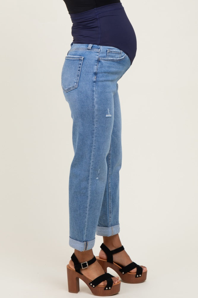 woman wearing light blue distressed maternity jeans with a black top and showing her baby bump