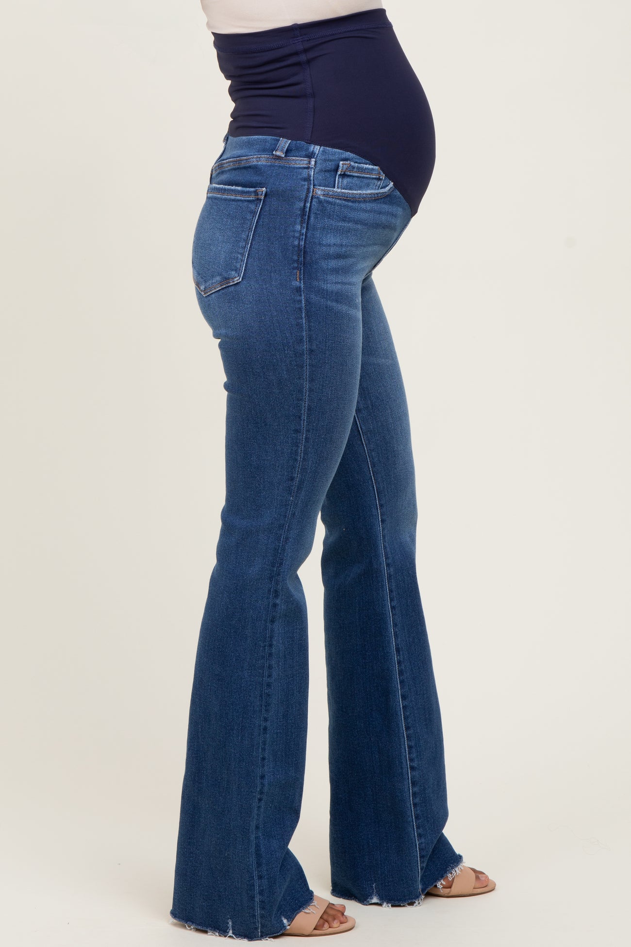woman wearing dark blue maternity flared jeans, showing a visible baby bump