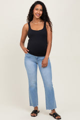 woman wearing a black scoop neck maternity tank top and light blue flared jeans, showing her baby bump
