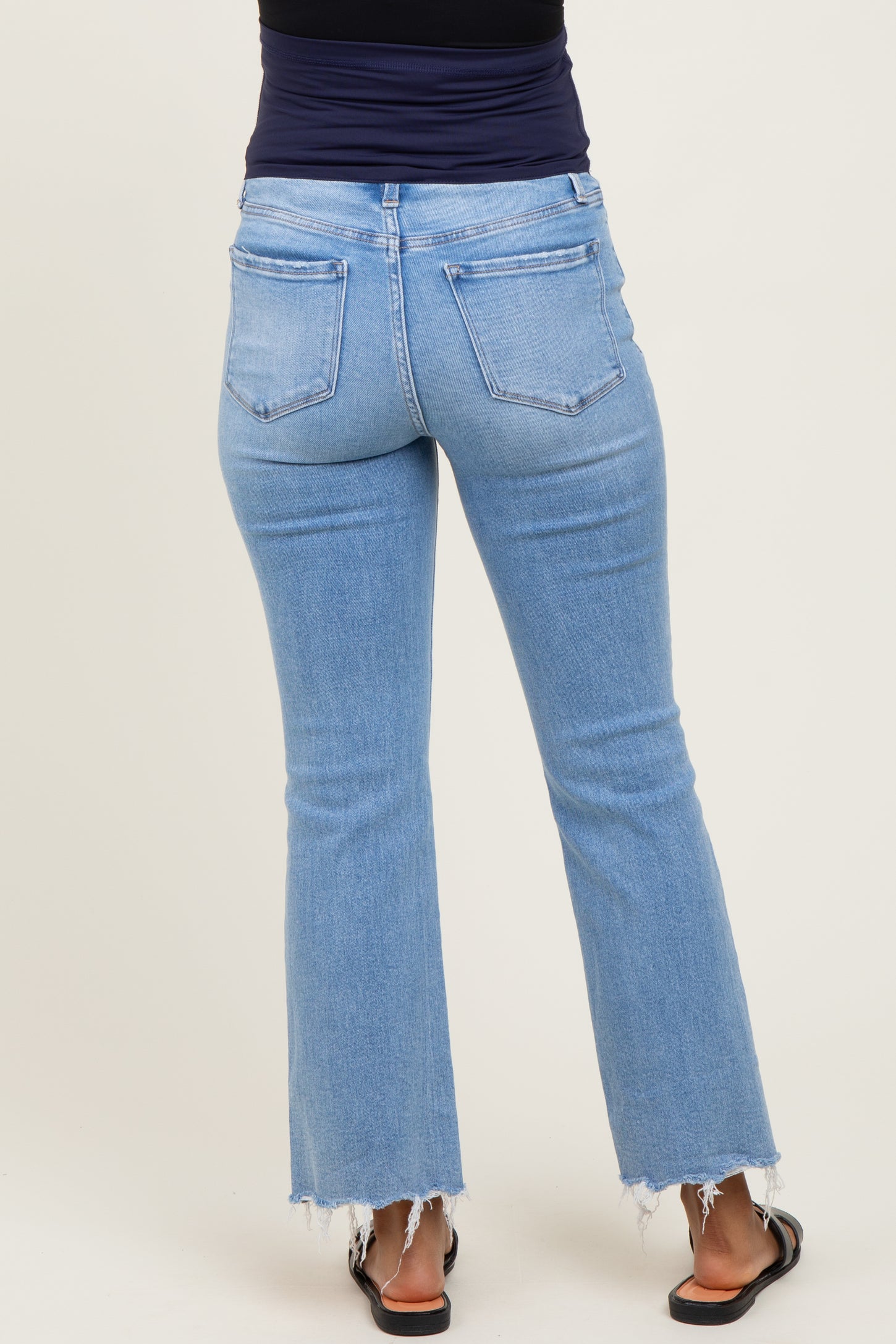 woman wearing light blue maternity flared jeans with a raw hem, viewed from the back