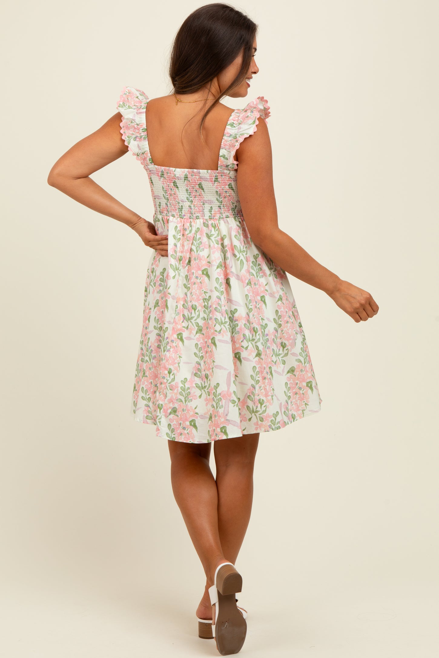 woman wearing a floral print maternity dress with ruffled sleeves and a smocked back, showing a baby bump