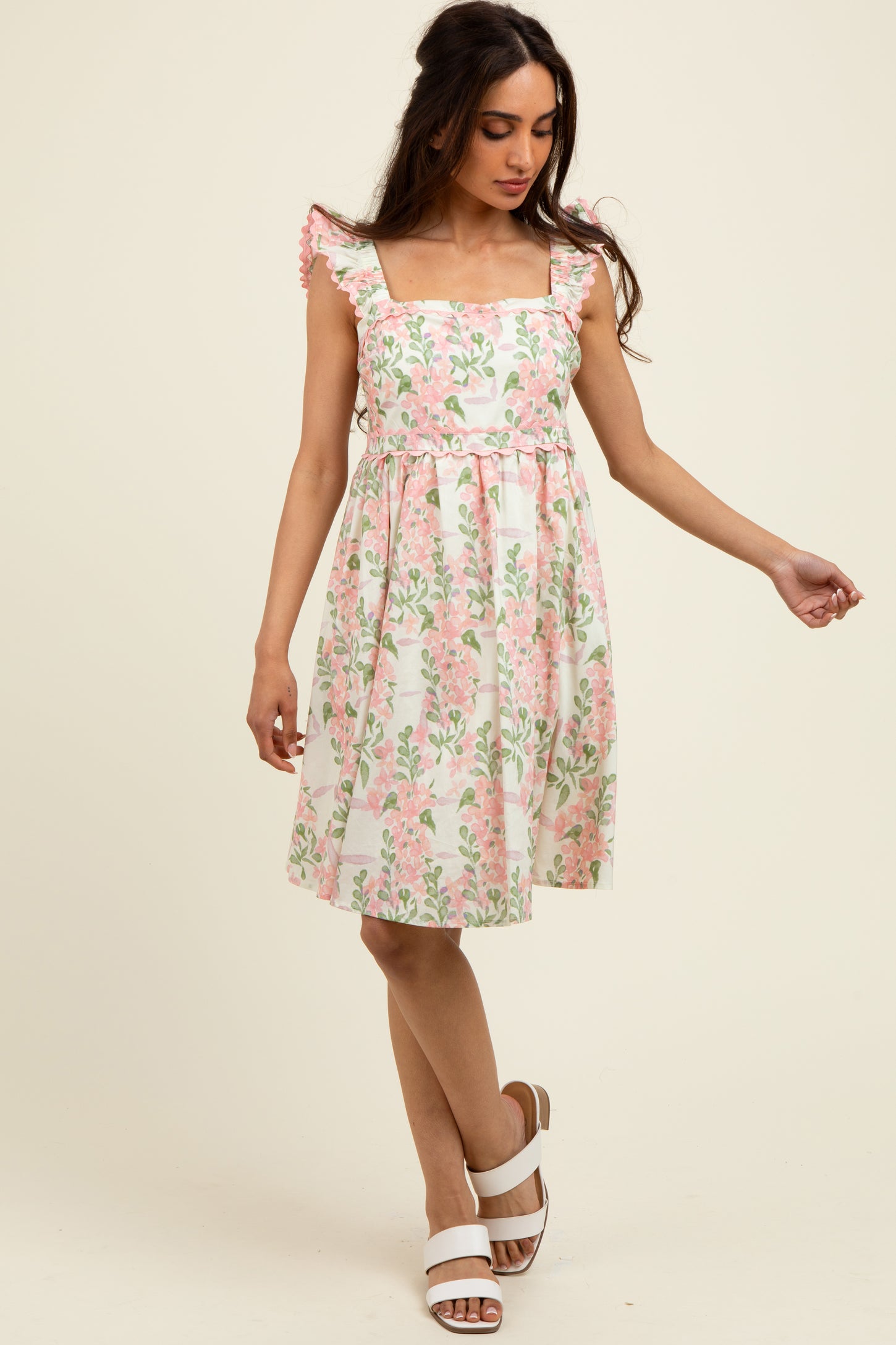 woman wearing a floral print midi dress with cap sleeves and a fitted waist in pink and white