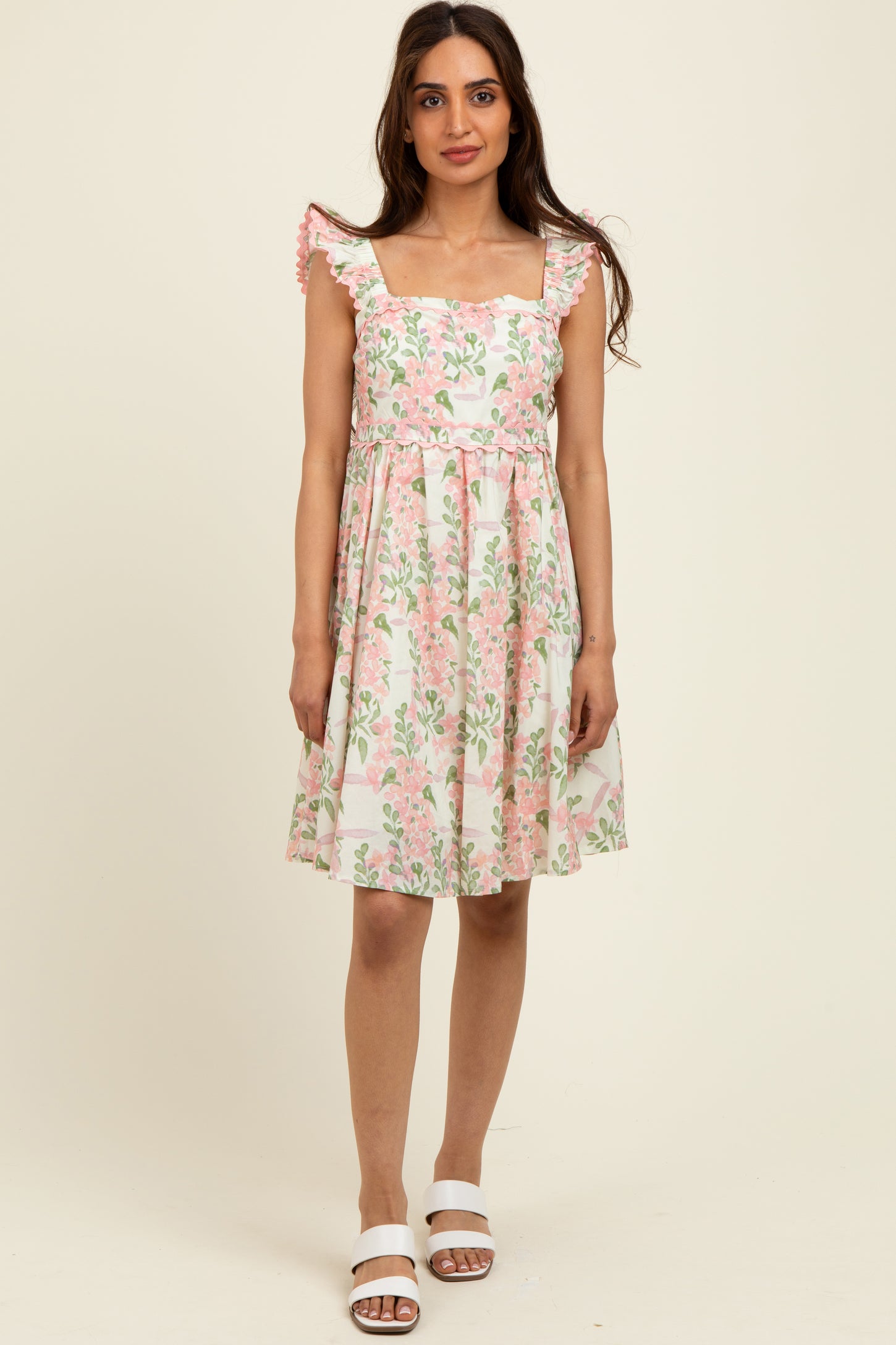 woman wearing a floral print sundress with square neckline and ruffled sleeves, posed against a neutral background