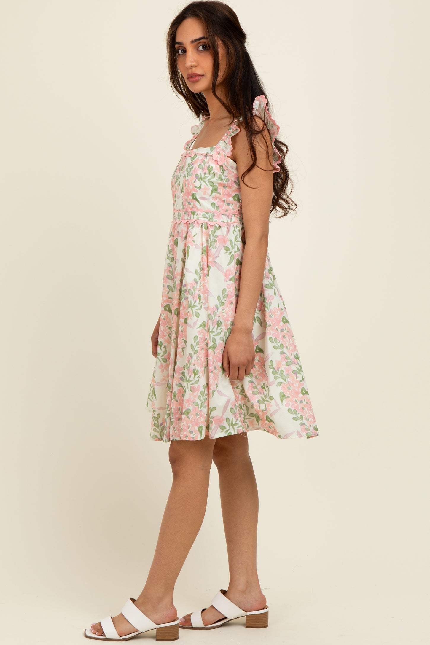 woman wearing a floral pattern midi dress with shoulder bows and a flared skirt, paired with white sandals