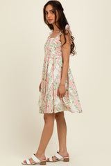 woman wearing a floral pattern midi dress with shoulder bows and a flared skirt, paired with white sandals