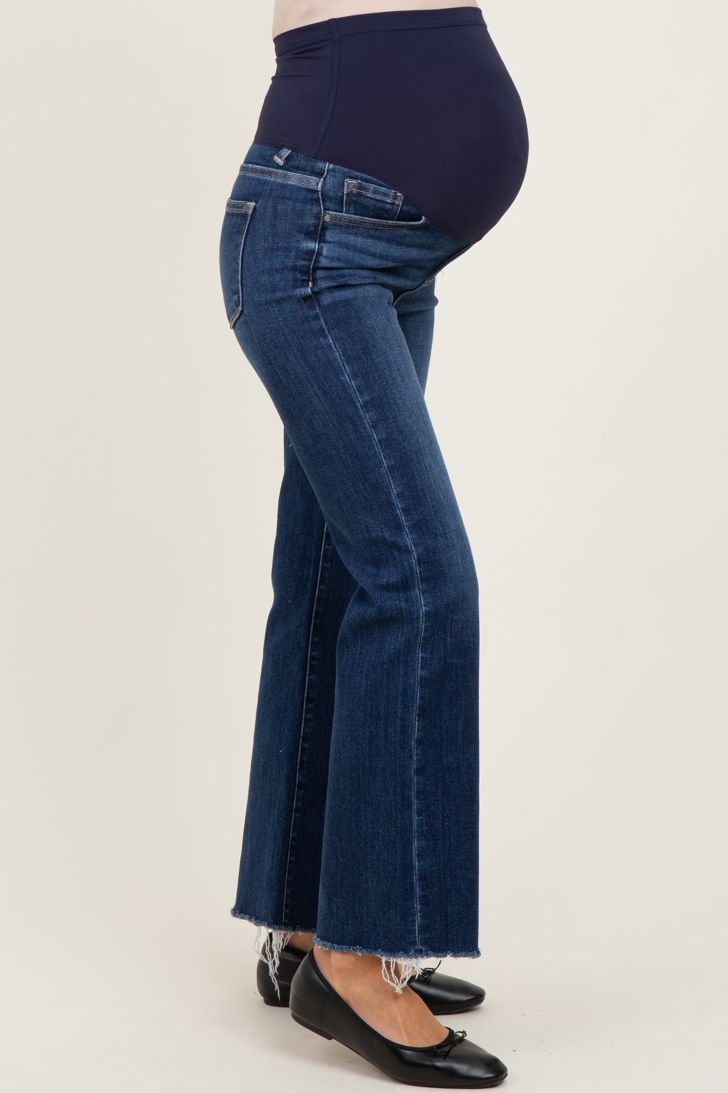 woman wearing dark blue maternity flared jeans with a high waistband and visible baby bump