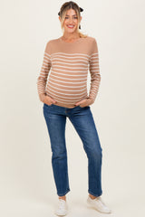 woman wearing a beige striped maternity sweater and blue jeans, displaying her baby bump