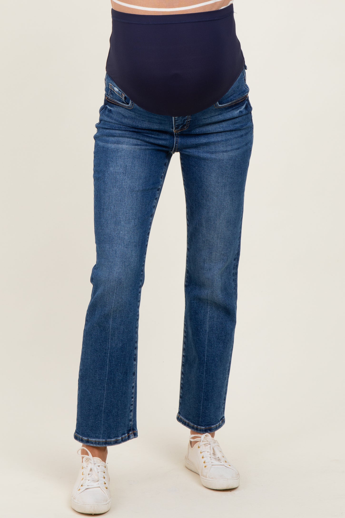 woman wearing dark blue maternity jeans with a supportive belly panel and white sneakers