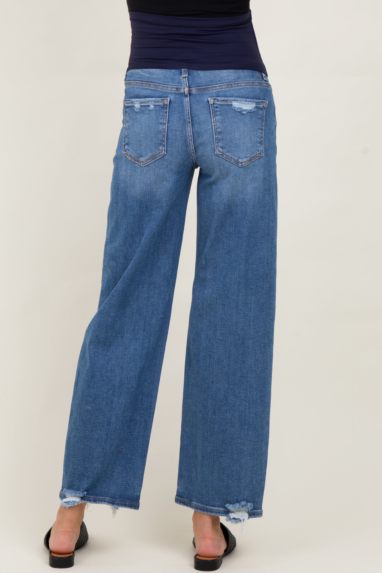 woman wearing a pair of distressed blue maternity wide-leg jeans, showing the back view with a relaxed fit