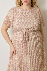 woman wearing a light pink floral plus size dress with short sleeves and a tie waist detail
