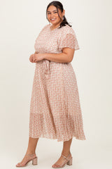 woman wearing a light pink floral plus size midi dress with short sleeves and a tie waist detail