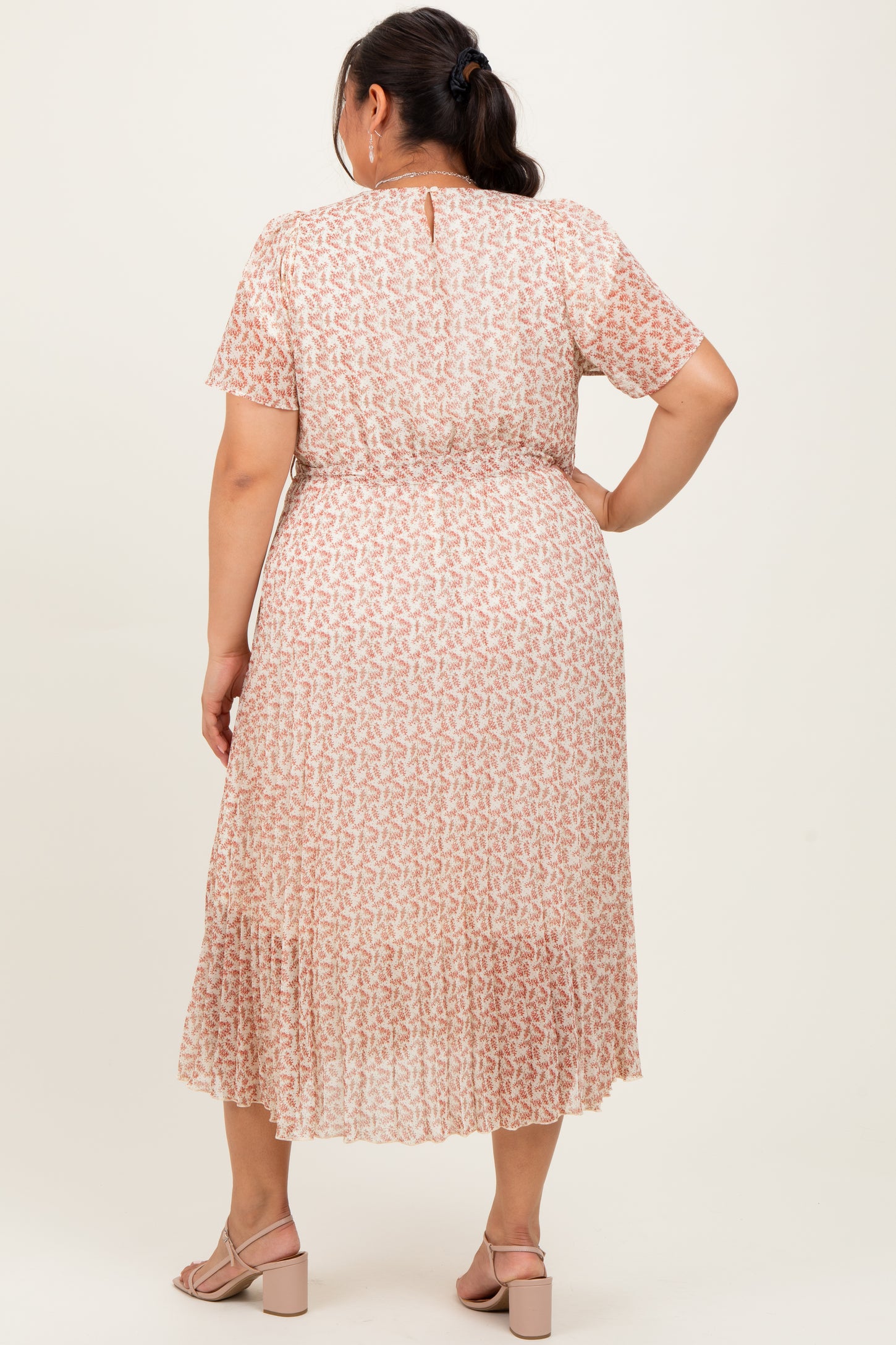 woman wearing a light pink plus size maxi dress with a floral pattern and short sleeves, seen from the back