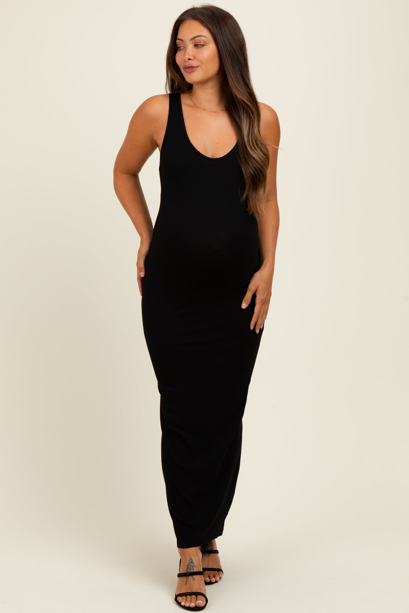 woman wearing a black ribbed sleeveless maternity maxi dress and showing her baby bump