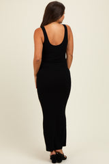woman wearing a black ribbed maternity maxi dress, view from the back, showing a fitted silhouette