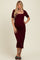 woman wearing a burgundy short sleeve ribbed maternity dress, showing her baby bump