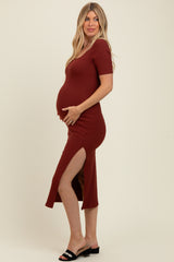 woman wearing a rust-colored short sleeve maternity dress with side slits and a visible baby bump