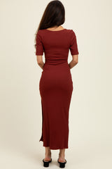 woman wearing a rust-colored ribbed maxi dress with short sleeves and a side slit, seen from the back