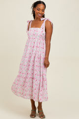 woman wearing a pink floral midi dress with tie straps and a tiered skirt