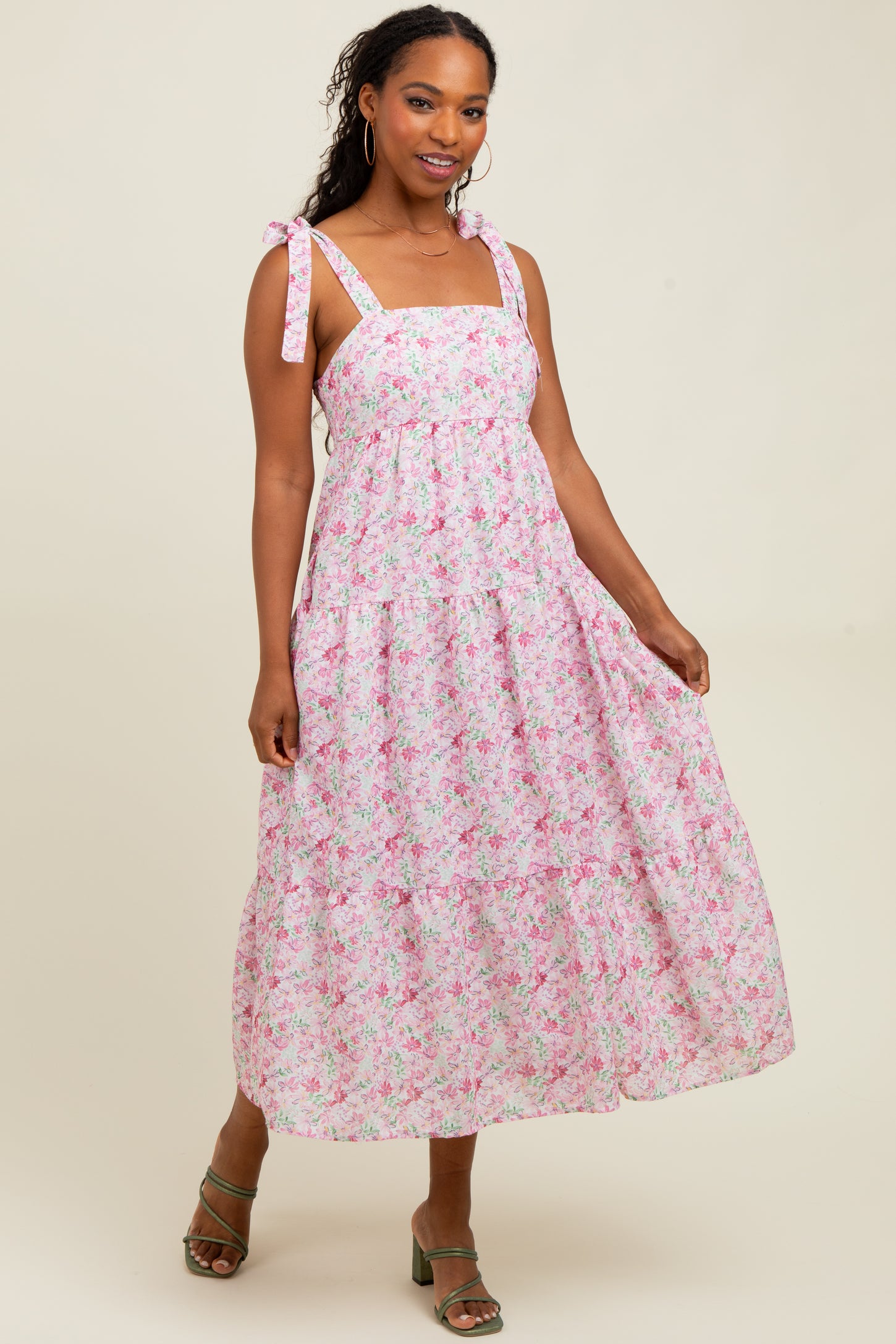 woman wearing a pink floral maxi dress with adjustable tie straps and a flowy skirt