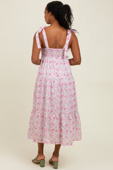 woman wearing a pink floral midi dress with tie straps and a smocked bodice, shown from the back