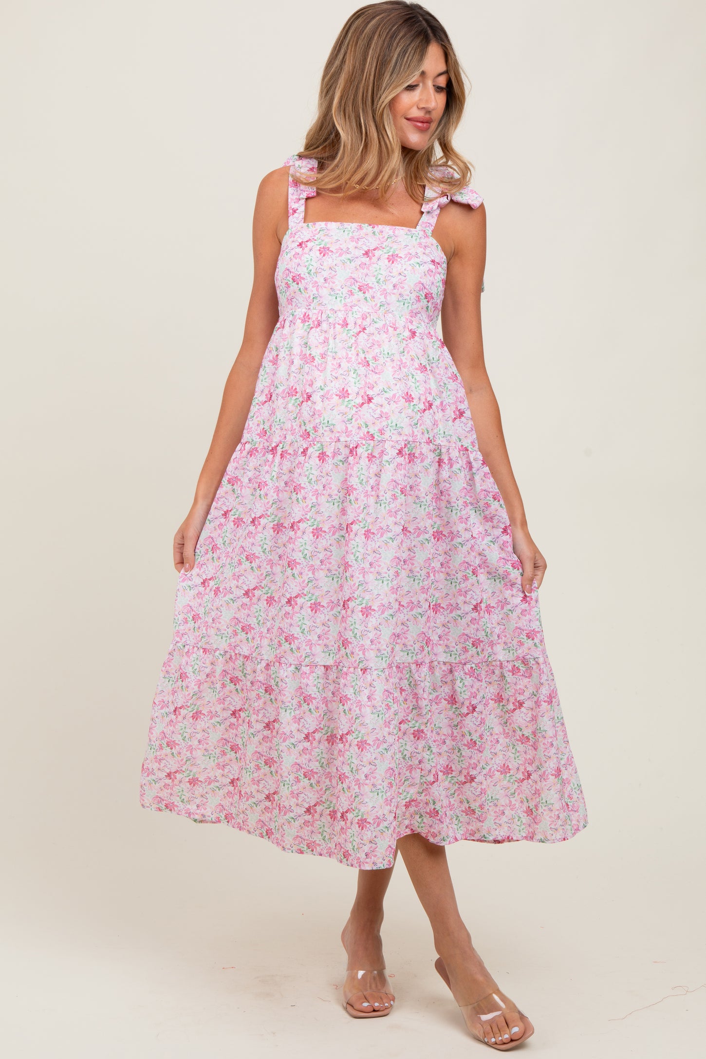 woman wearing a pink floral maternity dress with ruffled straps and a flowing skirt
