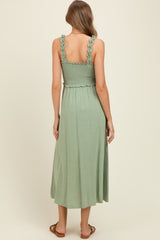 woman wearing a mint green maternity dress with ruffled straps and a smocked bodice, showing a baby bump from the back