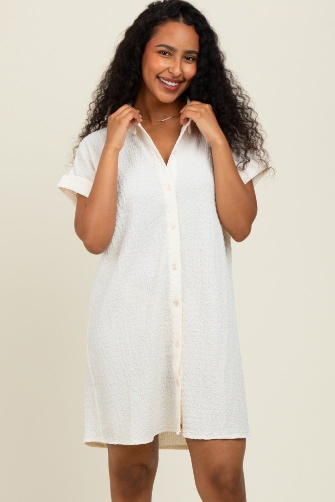 woman wearing a light beige short sleeve button-up shirt dress with a relaxed fit and textured fabric