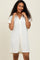 woman wearing a light beige short sleeve button-up shirt dress with a relaxed fit and textured fabric