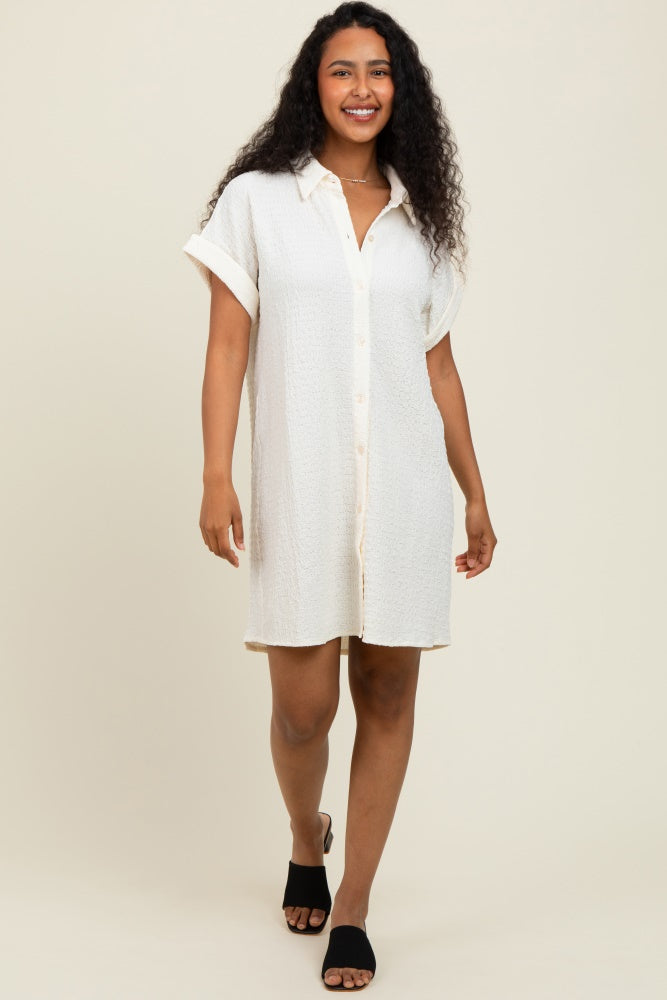 woman wearing a cream button-up short sleeve shirt dress with a relaxed fit and rolled cuffs