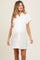 woman wearing a white maternity shirt dress with rolled sleeves and button details, showcasing her baby bump
