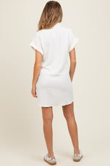 woman wearing a white short sleeve maternity dress with rolled cuffs, showing the back view