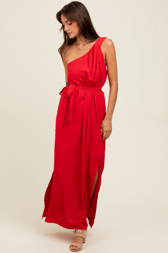 woman wearing a red one-shoulder maxi dress with a tie waist and side slits