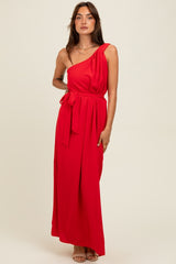 woman wearing a red one-shoulder maxi dress with a belted waist and flowing silhouette