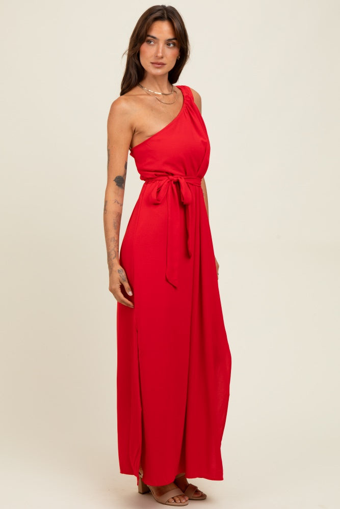 woman wearing a red one-shoulder maxi dress with a tied waist and side slit