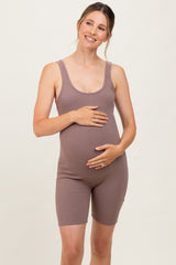 woman wearing a brown ribbed maternity bodysuit and holding her baby bump