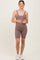 woman wearing a mauve ribbed maternity romper with a visible baby bump and white sneakers