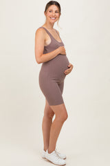 woman wearing a mauve ribbed maternity bodysuit, smiling and holding her baby bump