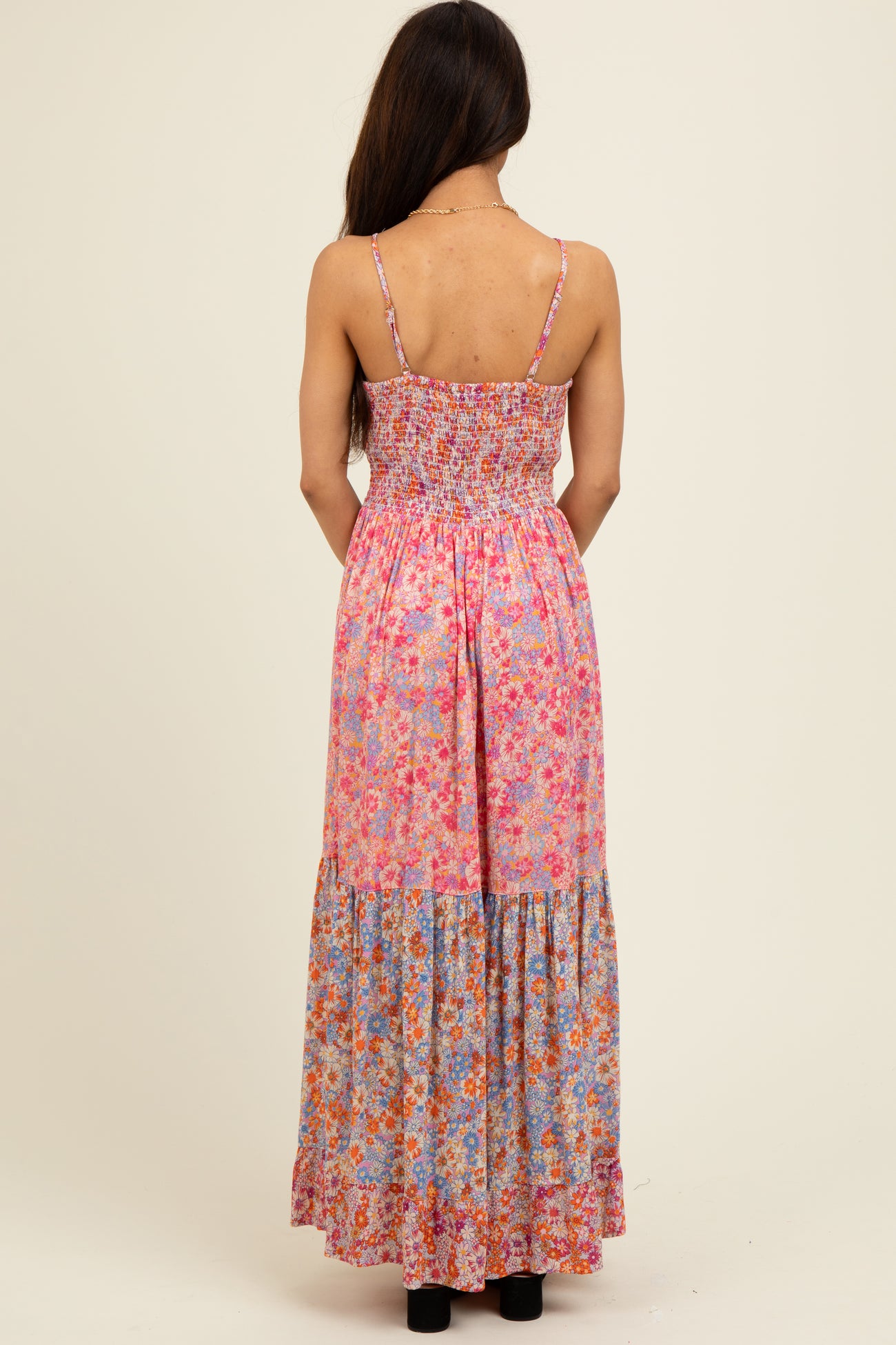 woman wearing a pink floral maxi dress with smocked bodice and tiered skirt, view from the back