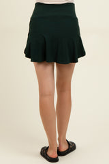 woman wearing a dark green maternity skort with a flared design, viewed from the back