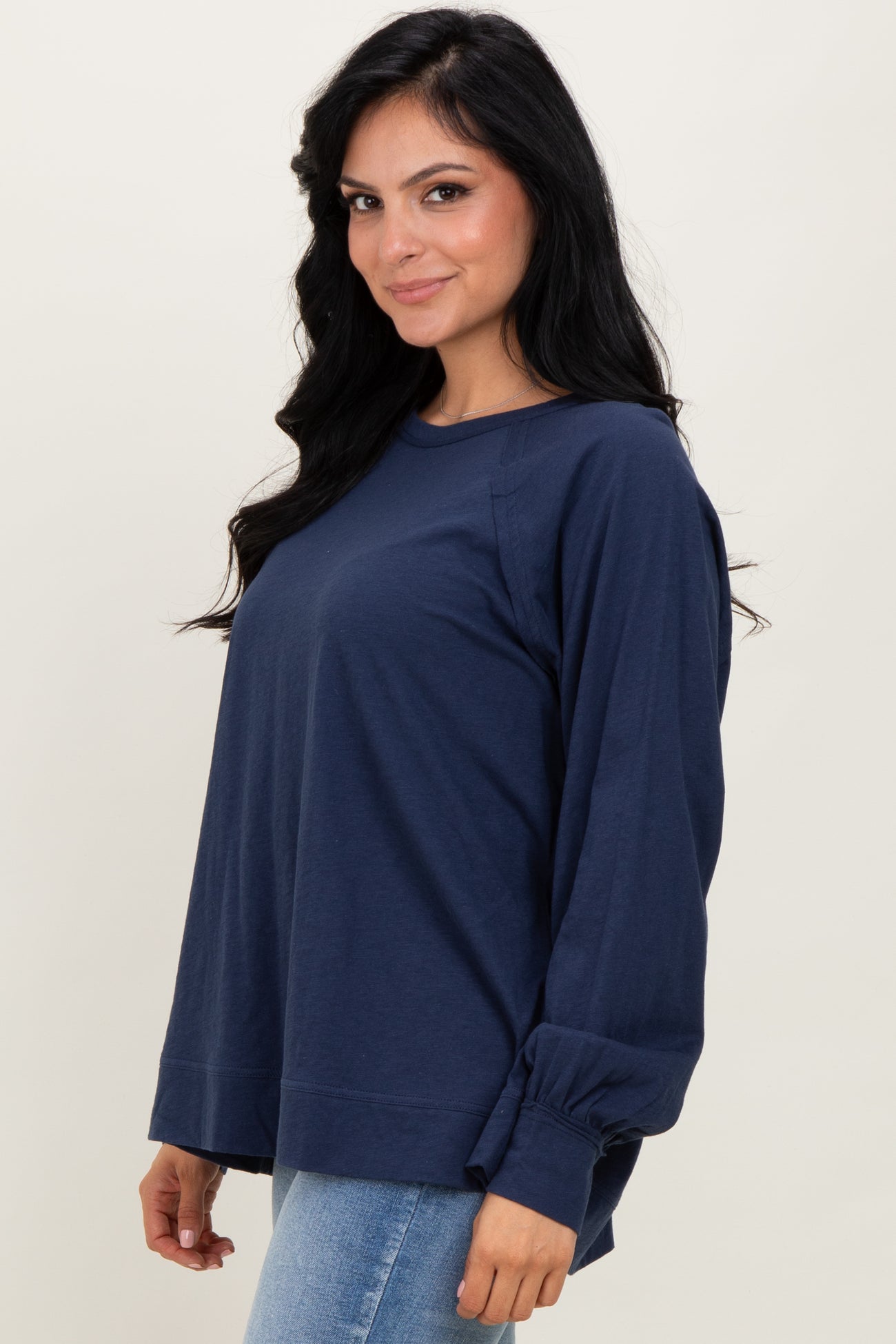 woman wearing a navy blue long sleeve top with a relaxed fit and gathered sleeve details