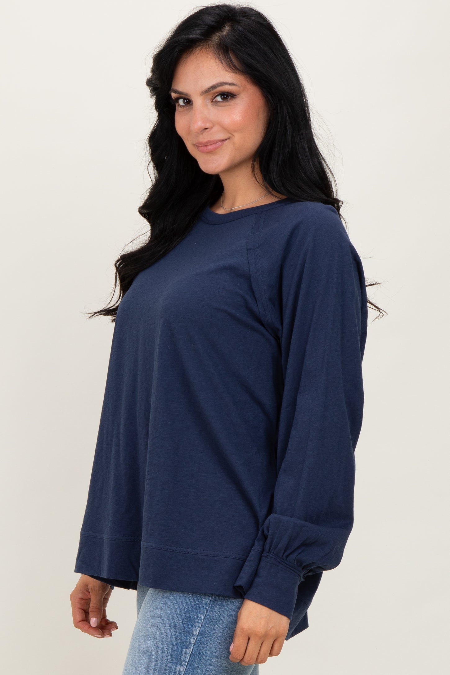 woman wearing a navy blue long sleeve top with a relaxed fit and gathered sleeve details