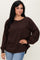 woman wearing a brown long sleeve top with a relaxed fit and raglan sleeves, paired with light blue jeans