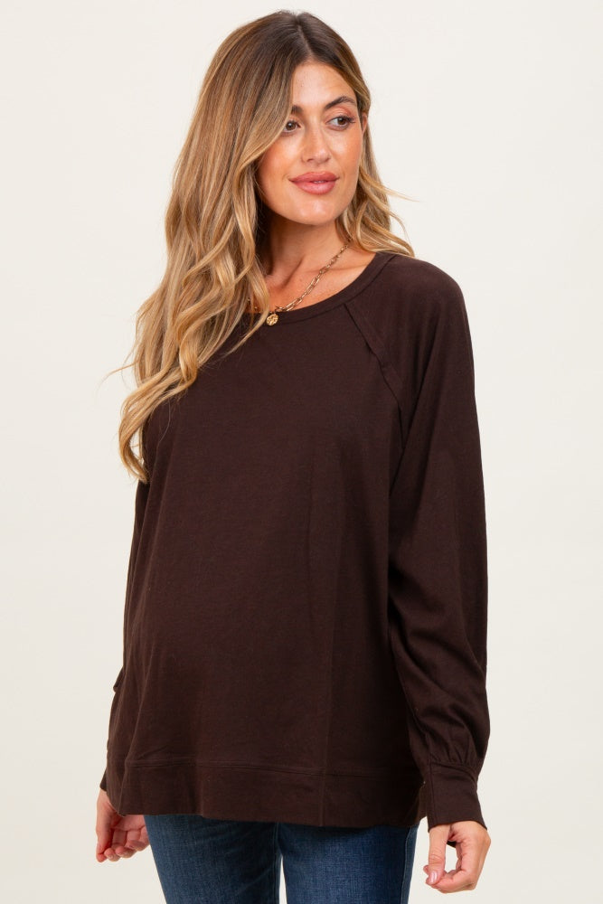 woman wearing a brown long sleeve maternity top with a relaxed fit and visible baby bump