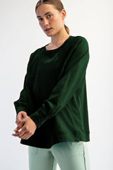 woman wearing a dark green long sleeve top with a relaxed fit and raglan sleeves