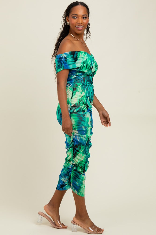 woman wearing a vibrant off-the-shoulder green and blue printed midi dress with ruched detailing